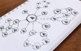 um caderno com desenhos de pessoas se interligando, mostrando o poder de um bom atendimento nas redes para a reputação da marca.